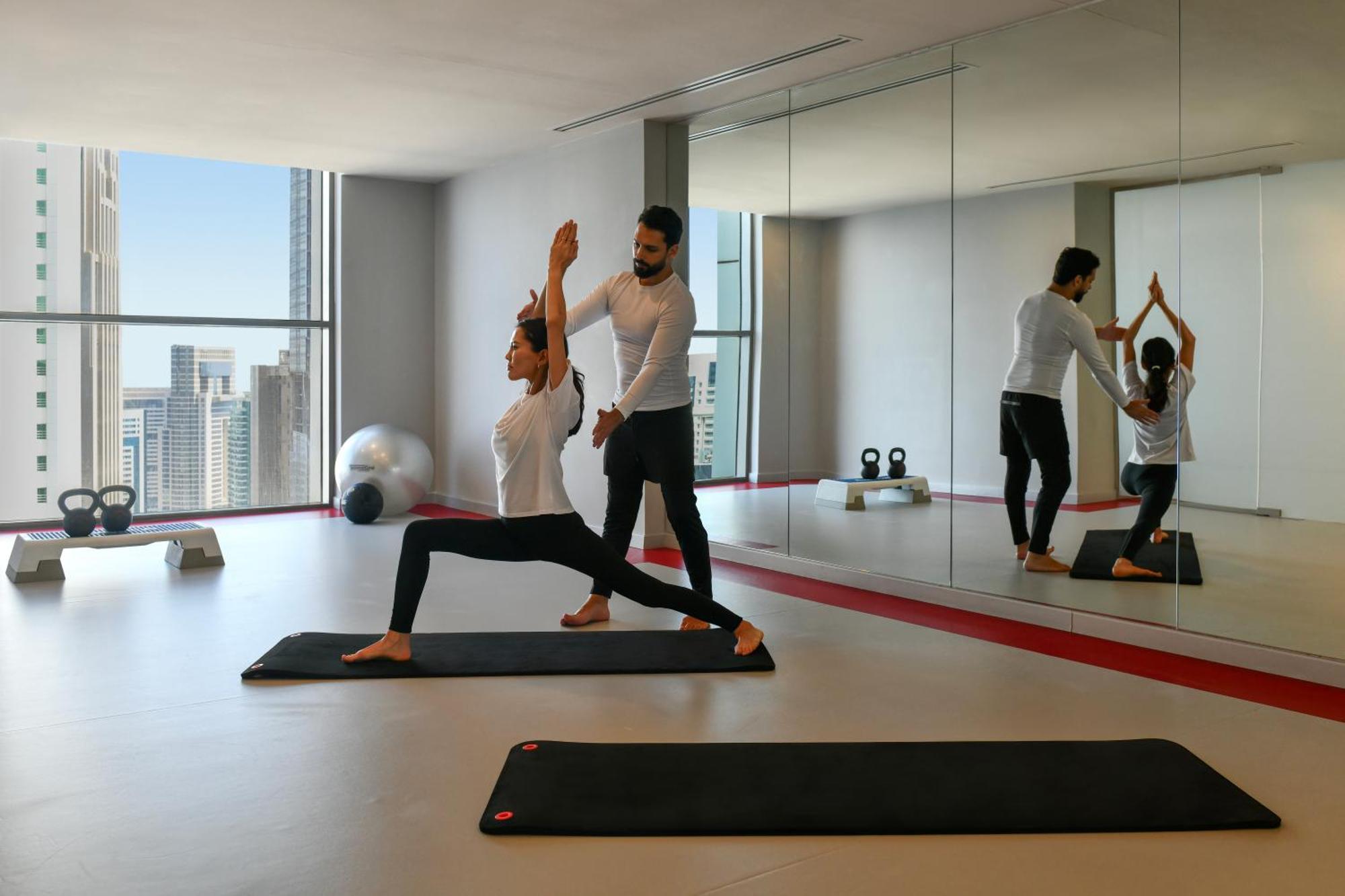 Dusit Doha Hotel Eksteriør billede A personal trainer assisting a woman with a yoga workout